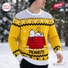 Front view of Peanuts Snoopy yellow ugly Christmas sweater worn outdoors in the snow.