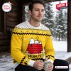 Man wearing Peanuts Snoopy Yellow Ugly Christmas Sweater holding a mug outdoors in snow.