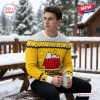 Man wearing a yellow Peanuts Snoopy ugly Christmas sweater while holding a mug outdoors in winter.