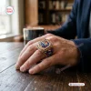 Closeup of a hand wearing the Pepsi 133rd Anniversary 1893 - 2026 Ring on a wooden table.