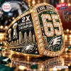 Closeup of a gold championship ring with number 65, trophies, and team logo.