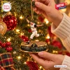 Closeup of hands hanging a baseball player figurine Christmas ornament on a tree.