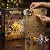 Hands opening a gold 2026 advent calendar with character figures and festive decorations.