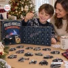 A smiling boy holding an ornament from a Police Vehicles Christmas Advent Calendar with miniature police vehicles displayed on a table.