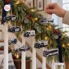 Close-up of a hand hanging police vehicle ornaments on a decorated evergreen garland for the holidays.
