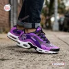 Side view of Prince Purple Air Max Plus Sport Shoes worn outdoors with cuffed jeans on a concrete sidewalk.