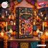 Front view of the Pueblo Del Dia de Muertos 2026 Advent Calendar box on a wooden table with candles and marigolds.