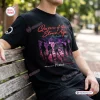 Front view of a Queens Of The Stone Age Tour Black Shirt worn by a person seated on a wooden bench.
