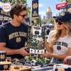 Man and woman holding Riddell Notre Dame Fighting Irish Mini Helmet Advent Calendar outdoors.