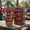 Red stainless steel tumbler with handle next to a matching gift box outdoors on a wooden table.