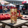 Front view of San Francisco 49ers Gold 80th Anniversary Tumbler on a wooden picnic table during a tailgate event.