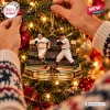 Closeup of hands hanging a San Francisco Giants Bobby Thomson Ornament on a glowing Christmas tree.