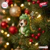 Close-up view of a basset hound figurine wearing a green dinosaur costume nestled in a Christmas tree.