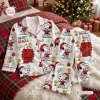 Front view of white Snoopy Christmas pajamas set featuring a holiday print with red collars and buttons.
