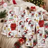 Flat lay of Snoopy Christmas pajamas set featuring a white button-down top and matching pants with festive holiday prints.