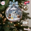 Close-up of a clear Happy Holidays snow globe ornament hanging on a tree with a beagle figure skating inside.