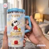 Close-up of a Snoopy Joe Cool Handle Tumbler held in hands, featuring a blue lid and cloud pattern.