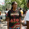 Woman wearing a black Soror Monique Juneteenth Black History Month Baseball Jersey outdoors in a park.
