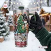 Hand holding a Star Wars Christmas Tree 40oz Tumbler Cup with festive character graphics in a snowy outdoor setting.