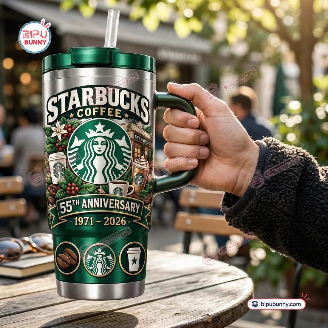 Hand holding the contoured emerald-green handle of the Starbucks 55th Anniversary 1971 - 2026 Handle Tumbler at an outdoor café table