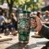 Hand holding a Starbucks 55th Anniversary 1971 - 2026 Handle Tumbler on an outdoor cafe table.