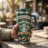Close-up of a person holding a green Starbucks 55th Anniversary 1971-2026 Tumbler with a handle.
