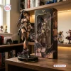 Front view of a Stellar Blade vinyl figure standing next to its branded retail box on a wooden desk.