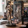 Front view of a Stellar Blade vinyl figure standing beside its packaging box on a wooden desk.