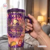 Hand holding a purple and orange tie dye Taco Bell 65th Anniversary Handle Tumbler with a straw.