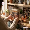 Person holding Tay 100 Weeks Billboard 200 Vinyl Figure in box near shelf.