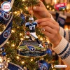 Closeup of hands hanging a Tennessee Titans Music City Miracle Christmas Ornament on a tree.