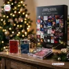 Front view of The Cure Cassette Tape Advent Calendar next to cassette cases on a wooden surface with Christmas tree lights.