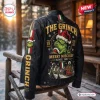 Back view of The Grinch Holiday Mischief Leather Jacket featuring green character graphics and text on a black background.