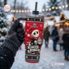 Gloved hand holding a red Stanley tumbler with holiday and skull patterns outdoors in winter.