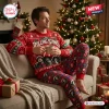Man wearing The Rolling Stones 2026 Christmas Sweater and Pants Set while holding a mug by a tree.