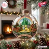 Hanging glass ornament depicting a fantasy scene with figures on a yellow road and a green castle.