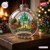 Front view of The Wizard Of Oz 87th Anniversary Glass Ornament featuring figures on a yellow brick road with a green castle.