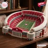High angle view of the University of Alabama plush stadium pillow resting on a wooden table.