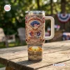 Front view of a US 250th Anniversary 1776-2026 Tumbler with eagle and flag design on a wooden table outdoors.