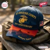 Front view of a blue and red US Marine Corps 250th Anniversary Baseball Cap resting on a green bag.