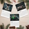 Top view of Willem Dafoe Classic Horror Monsters & Folklore 2027 Wall Calendar pages on a wooden surface with pine branches.