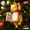 Hanging Winnie the Pooh Bookish and Bright Christmas Ornament holding an open book.