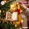 Closeup of Winnie the Pooh Bookish and Bright Christmas Ornament hanging on a pine tree holding an open book.