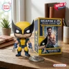 Front view of Wolverine Weapon X vinyl figure next to its yellow and blue packaging box on a wooden desk.
